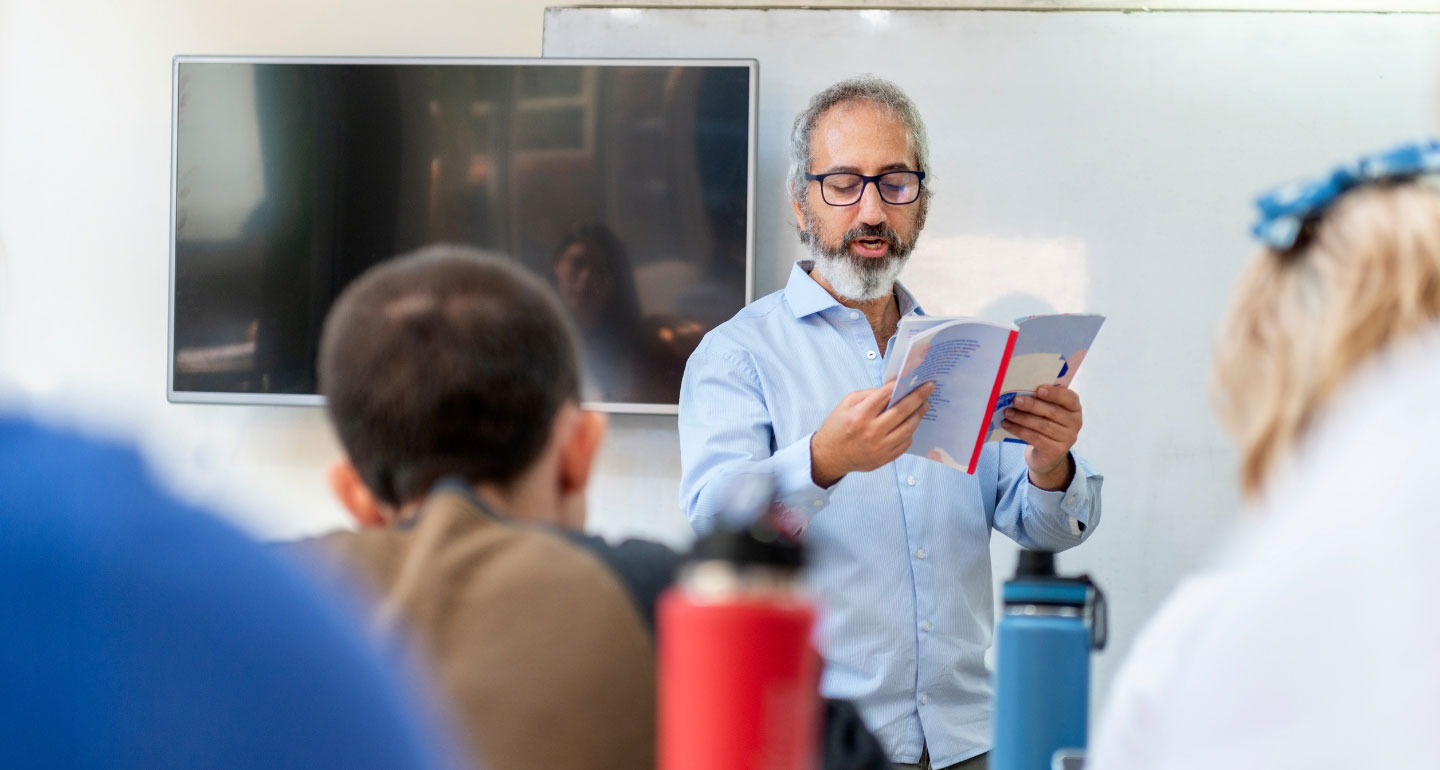 Teacher reading from book at the front of class - faculty resources - library