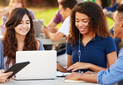 Group of students at a table outside studying with laptop and iPad - School of Education