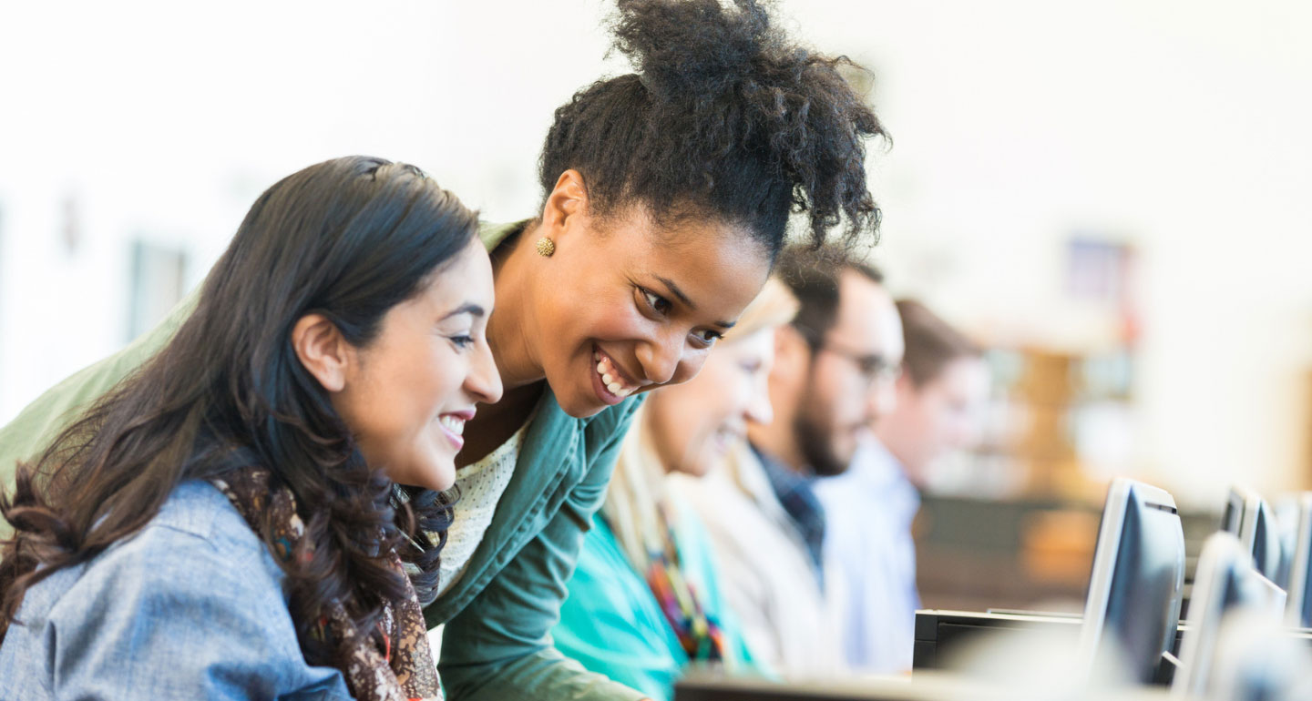 two female students, one looking down on the other's computer screen; transferoloy and transfer evaluation system