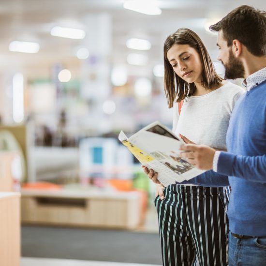 female and male student looking at a catalog in the library