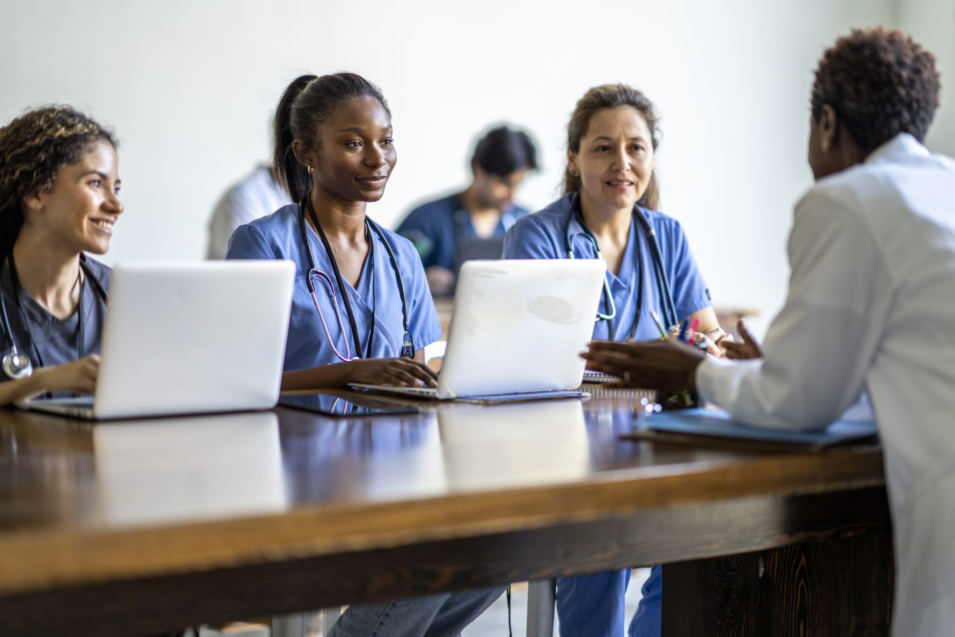Nursing students with laptops speaking with an instructor in the Nursing and Health program