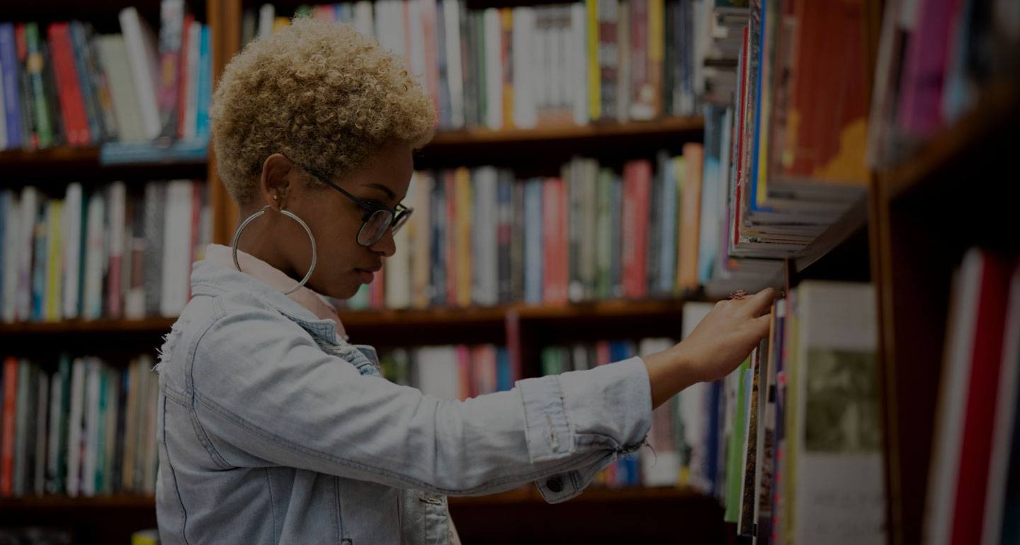 Female student reaching for a book on a library shelf; image has black overlay; Interlibrary Loan