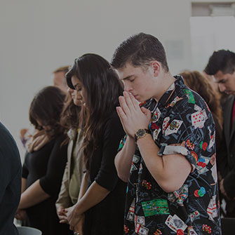 Male and female student bowing their heads in prayer