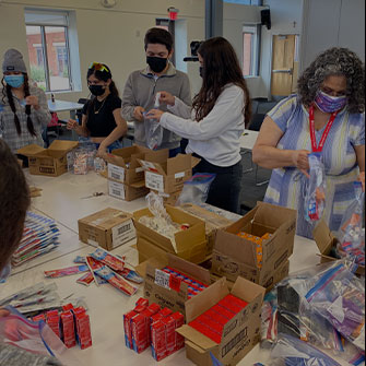 group of people with masks, packing up care boxes