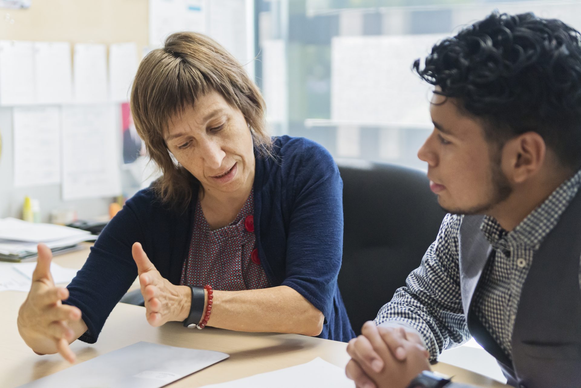 Counselling appointment for young Latino man student in counsellor College office.