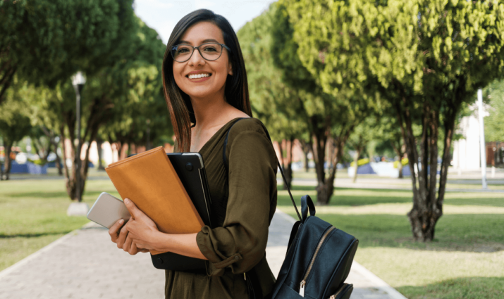female student holding books walking on quad - medical spanish program