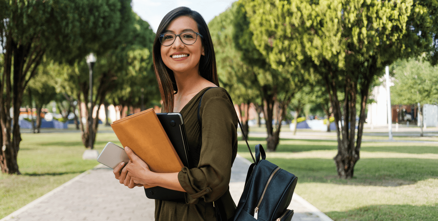 female student holding books walking on quad - medical spanish program