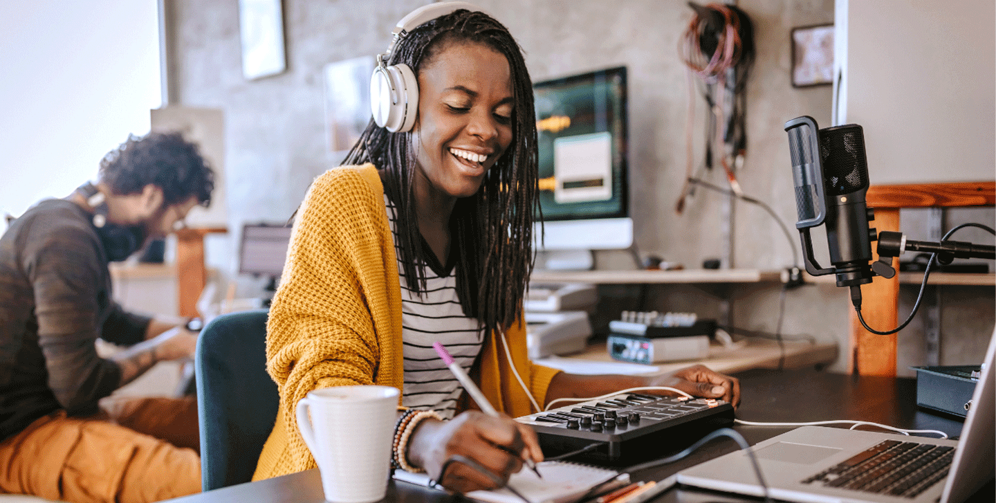 communication arts student writing with headphones at microphone
