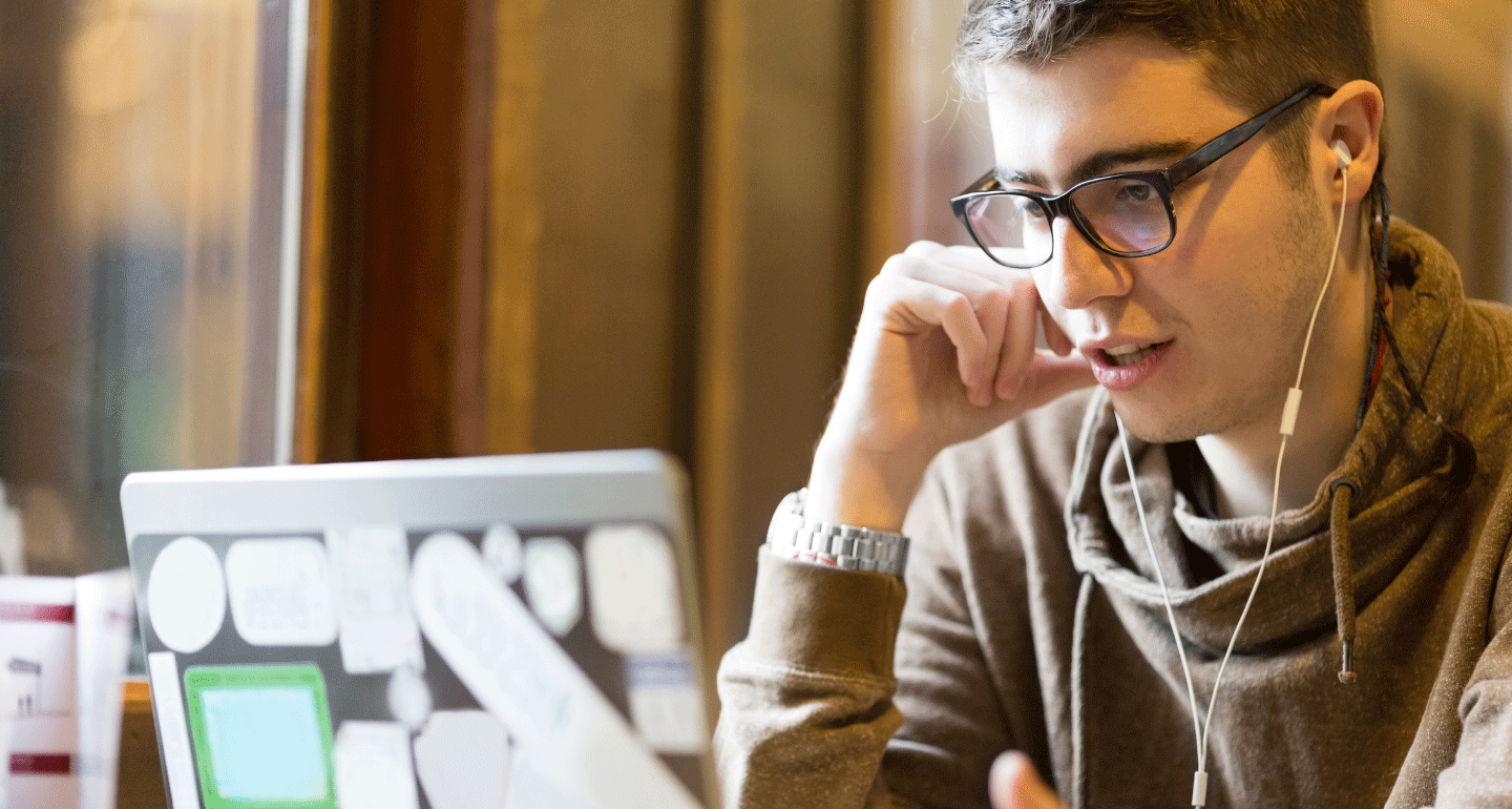 External and foreign credit. male student with ear buds looking at his laptop