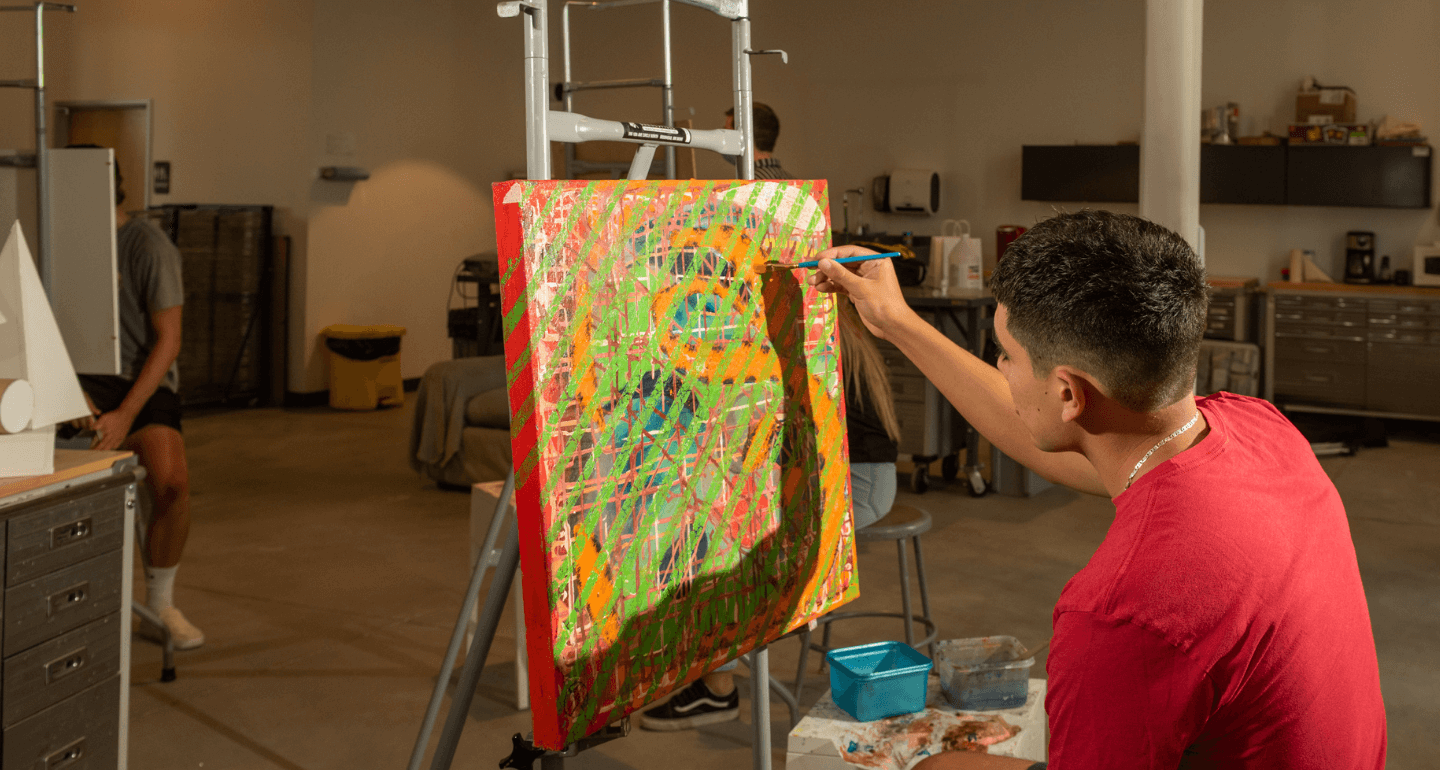 male student painting in art class