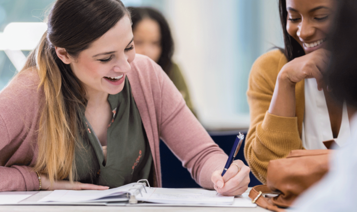 Writing program. Two female students at desk, one writing in notebook