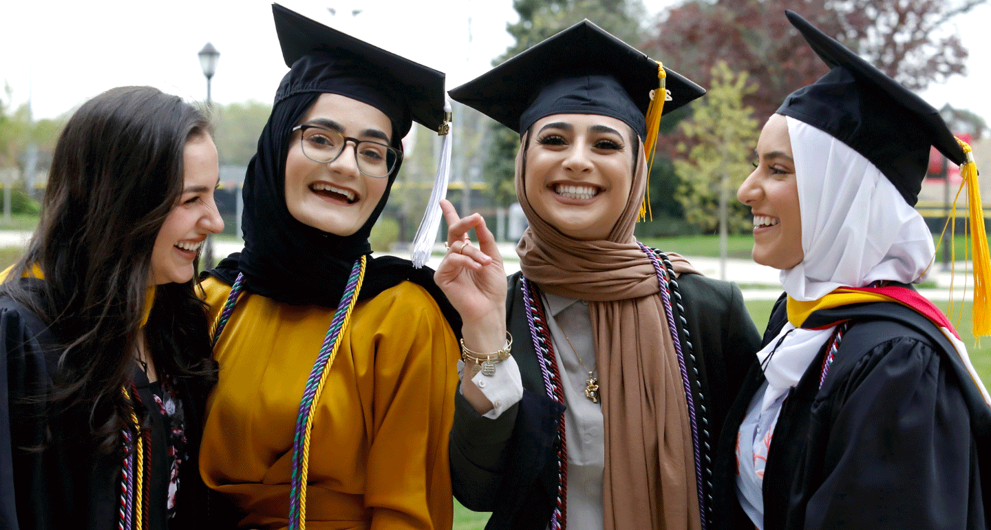 LEADS Scholarships available. four female students in caps and gowns at commencement