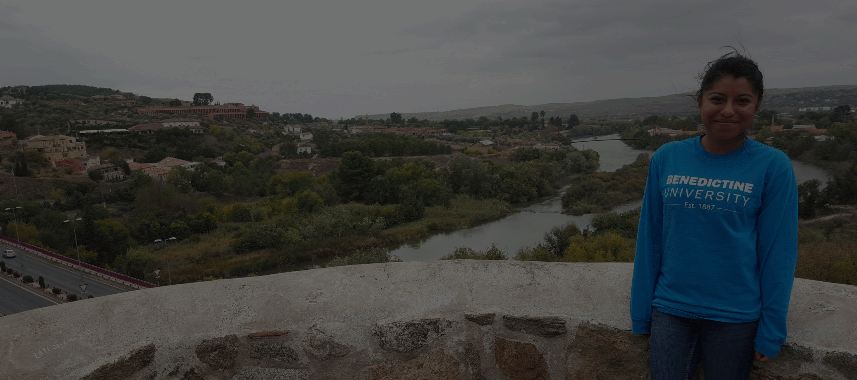 gray background - study abroad program; female student posing with scenic background