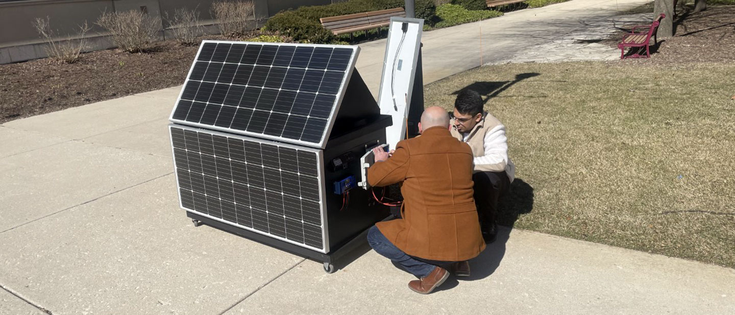 Stefanoski working with one of his research students on the portable solar array