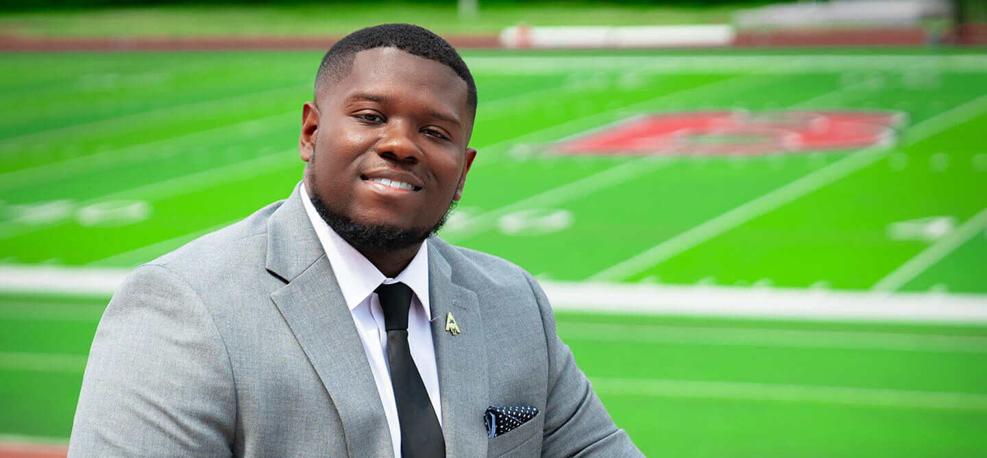 Football player alum posing by field